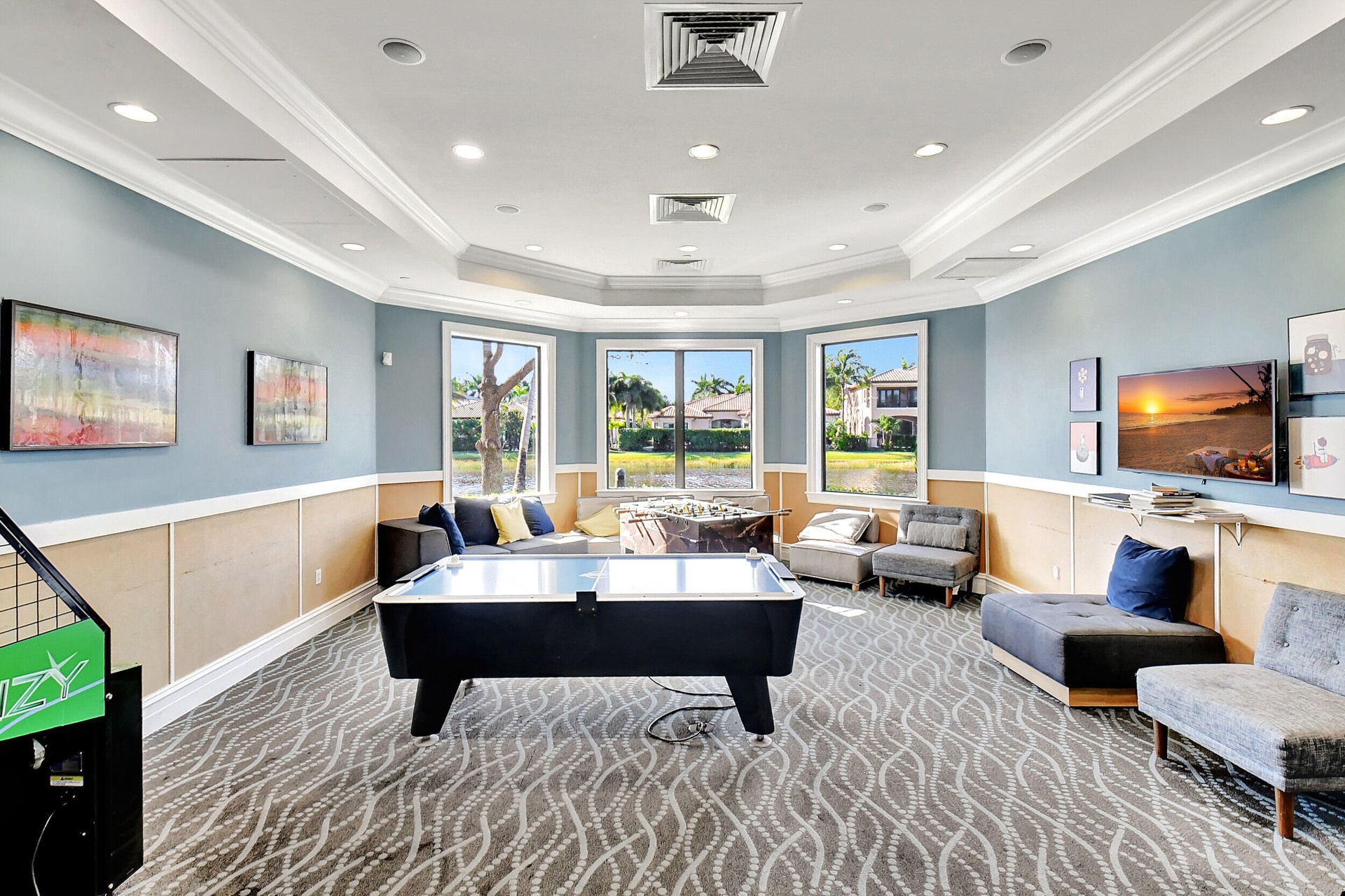 Spacious common area featuring patterned carpeting, tray ceilings with recessed lighting, and a bay window configuration