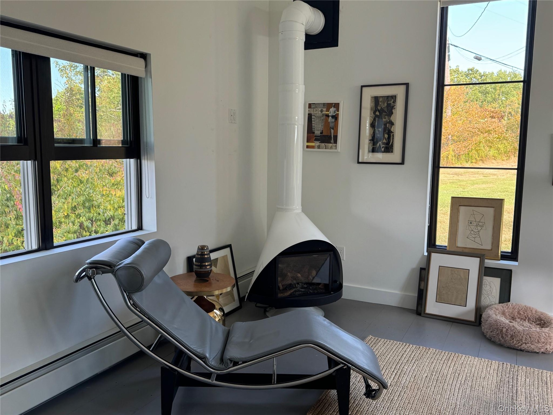 Sitting room with a wood stove, a baseboard heating unit, and tile patterned floors