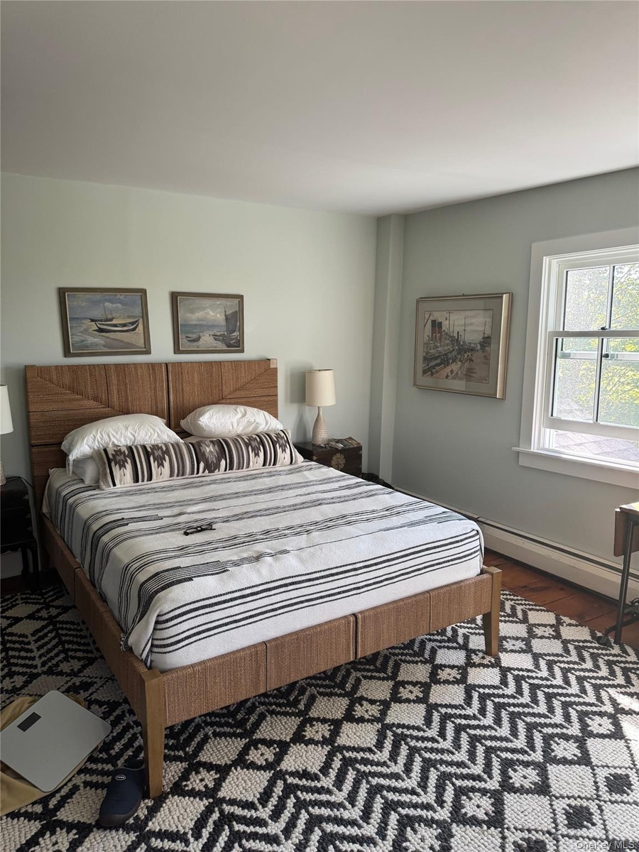 Bedroom with dark wood finished floors and a baseboard heating unit