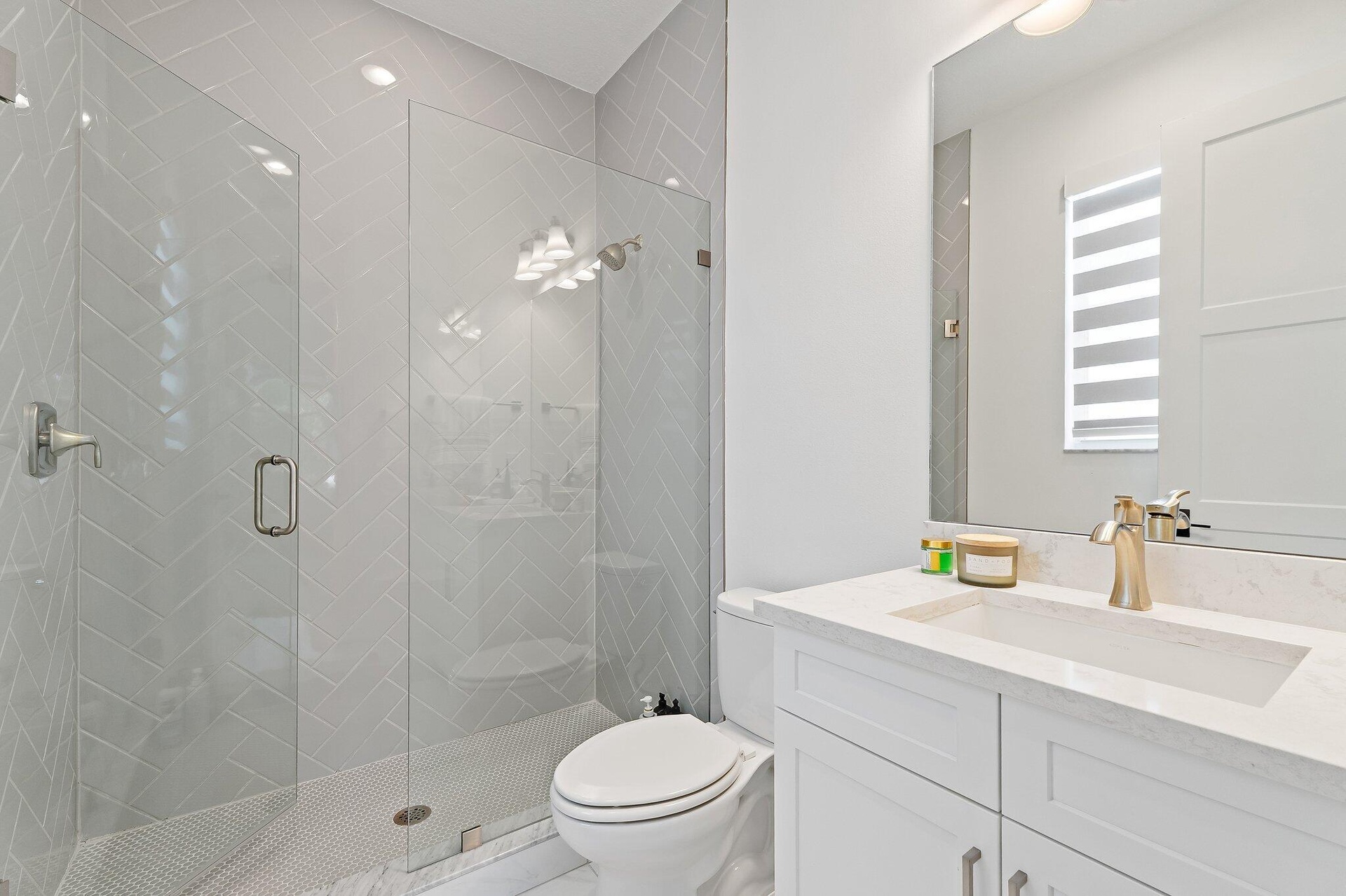 Bathroom with glass shower, white vanity, and marble tile