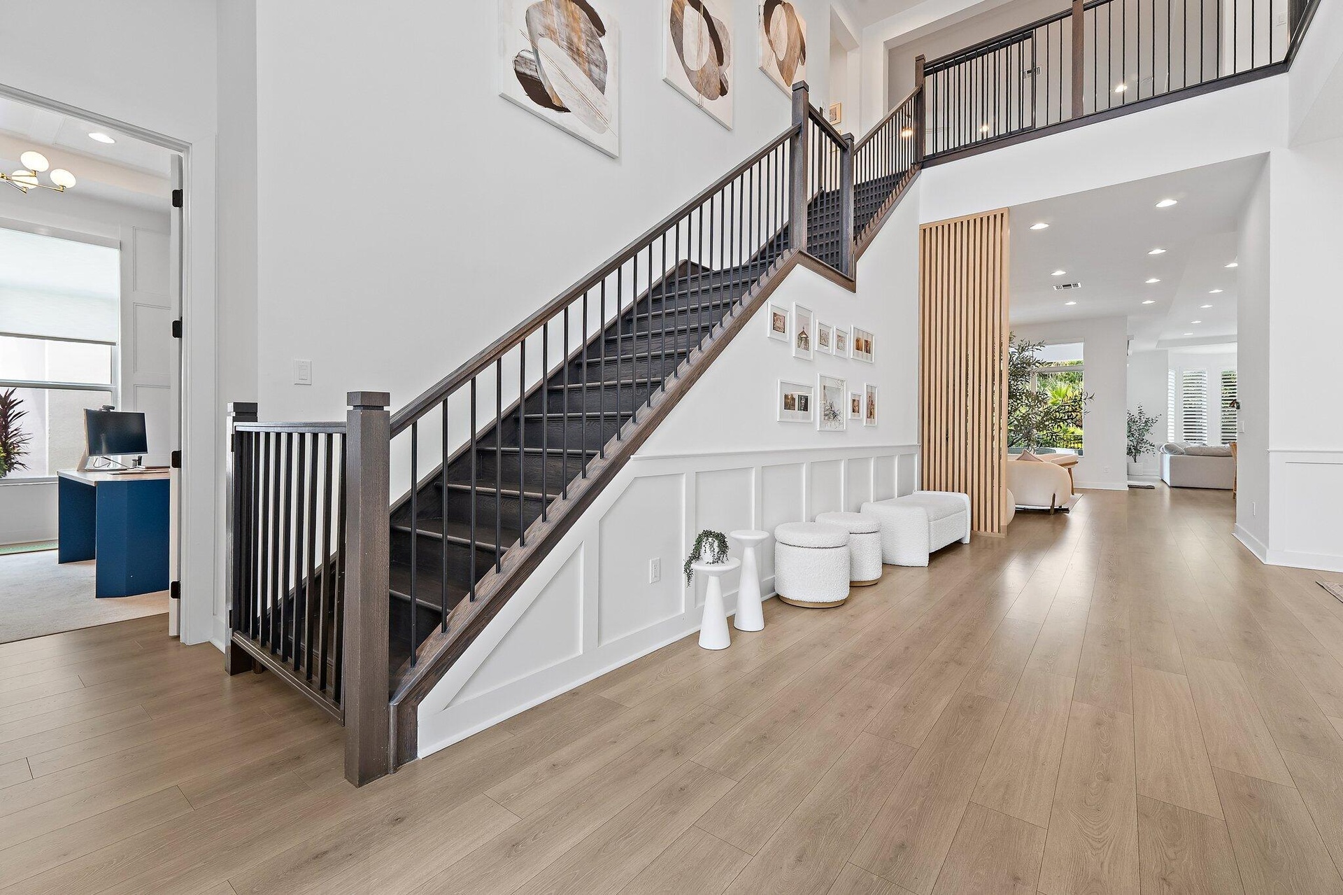 Foyer with staircase, black iron railing, gallery wall, and wood flooring