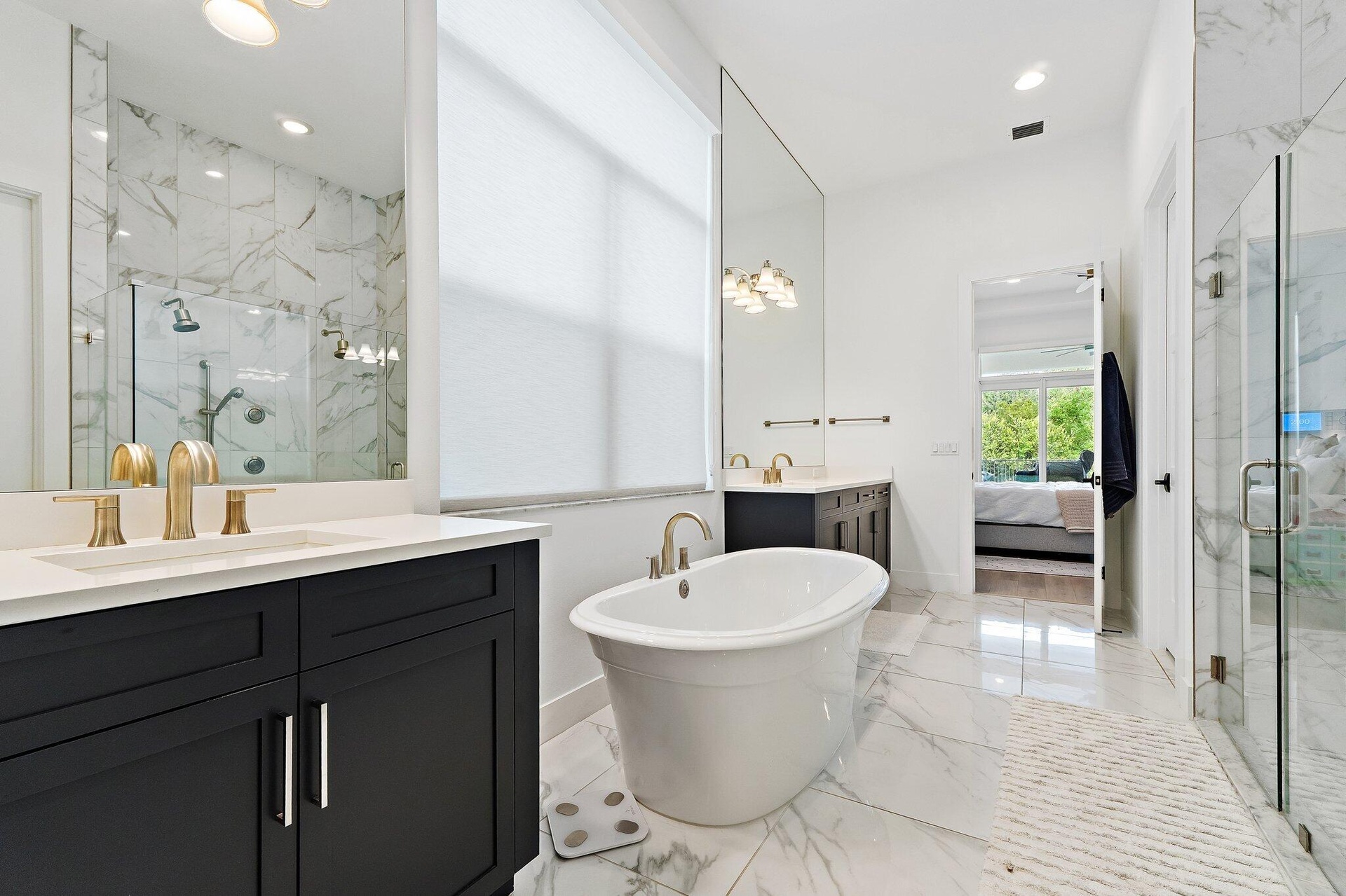 Bathroom with dark cabinetry, dual vanity, freestanding tub, and marble tile