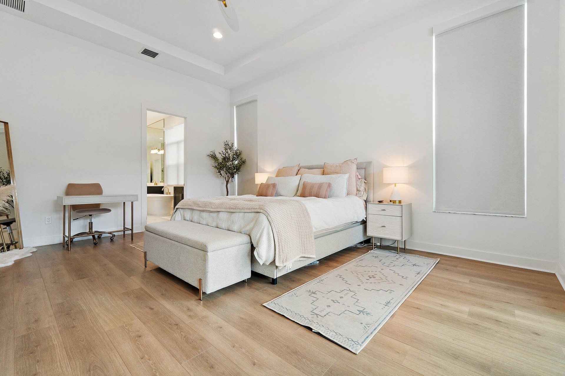 Bedroom with white bed, desk area, and wood flooring