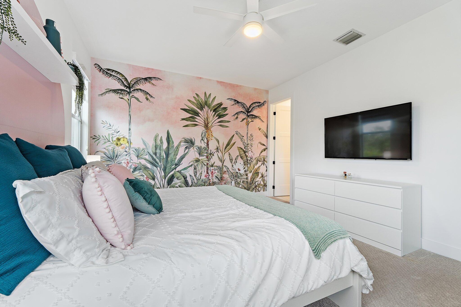 Bedroom with tropical palm mural, mounted TV, and dresser