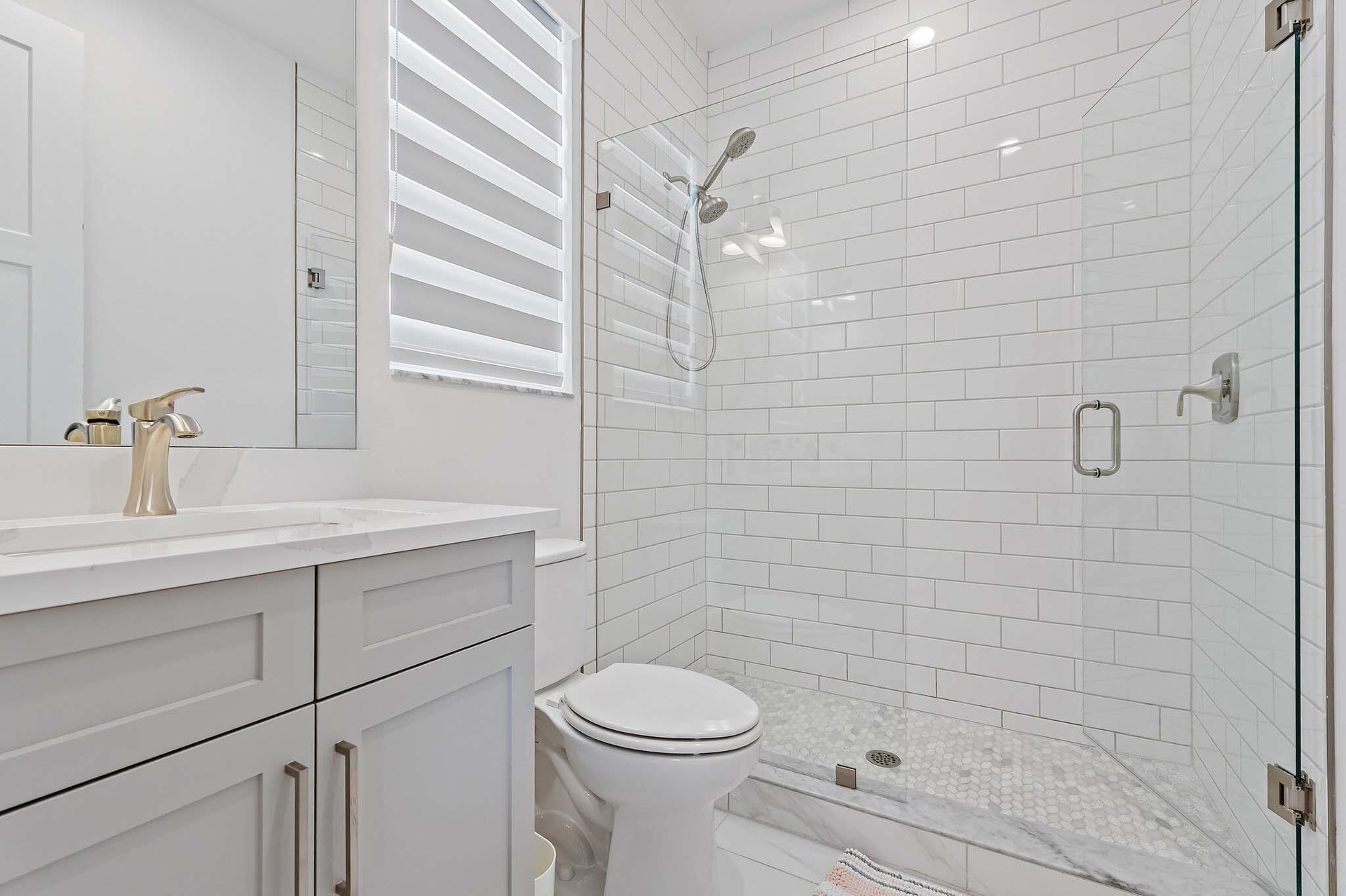 Bathroom with subway tile shower and gray vanity