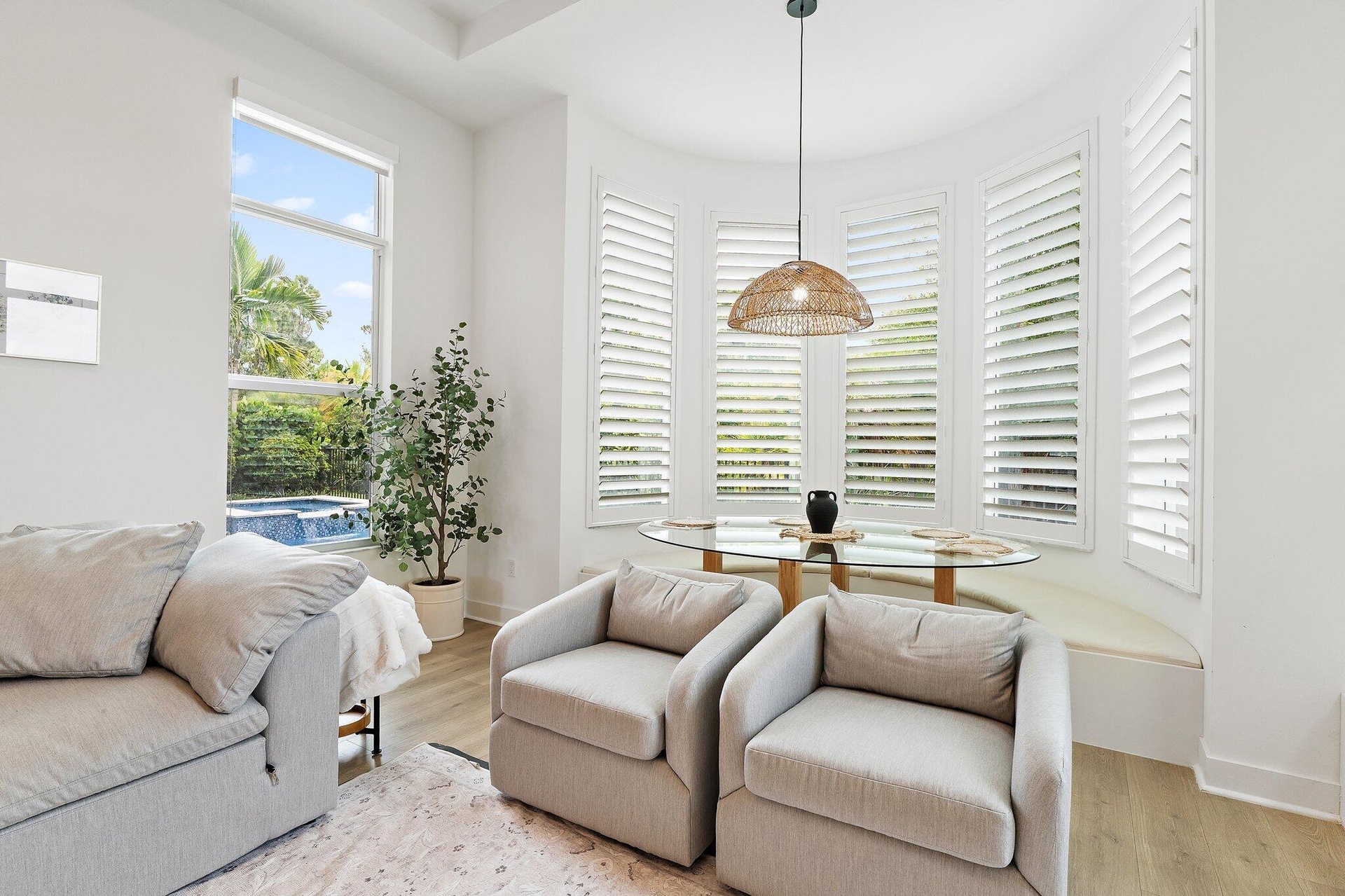 Sitting nook with bay window, armchairs, plantation shutters, and pool view
