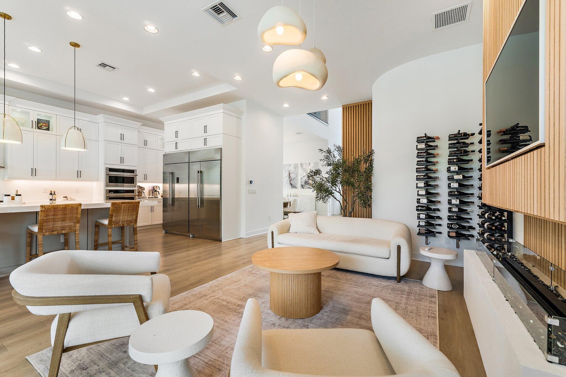 Sitting nook with swivel chairs, round side table, and wine display shelving near kitchen