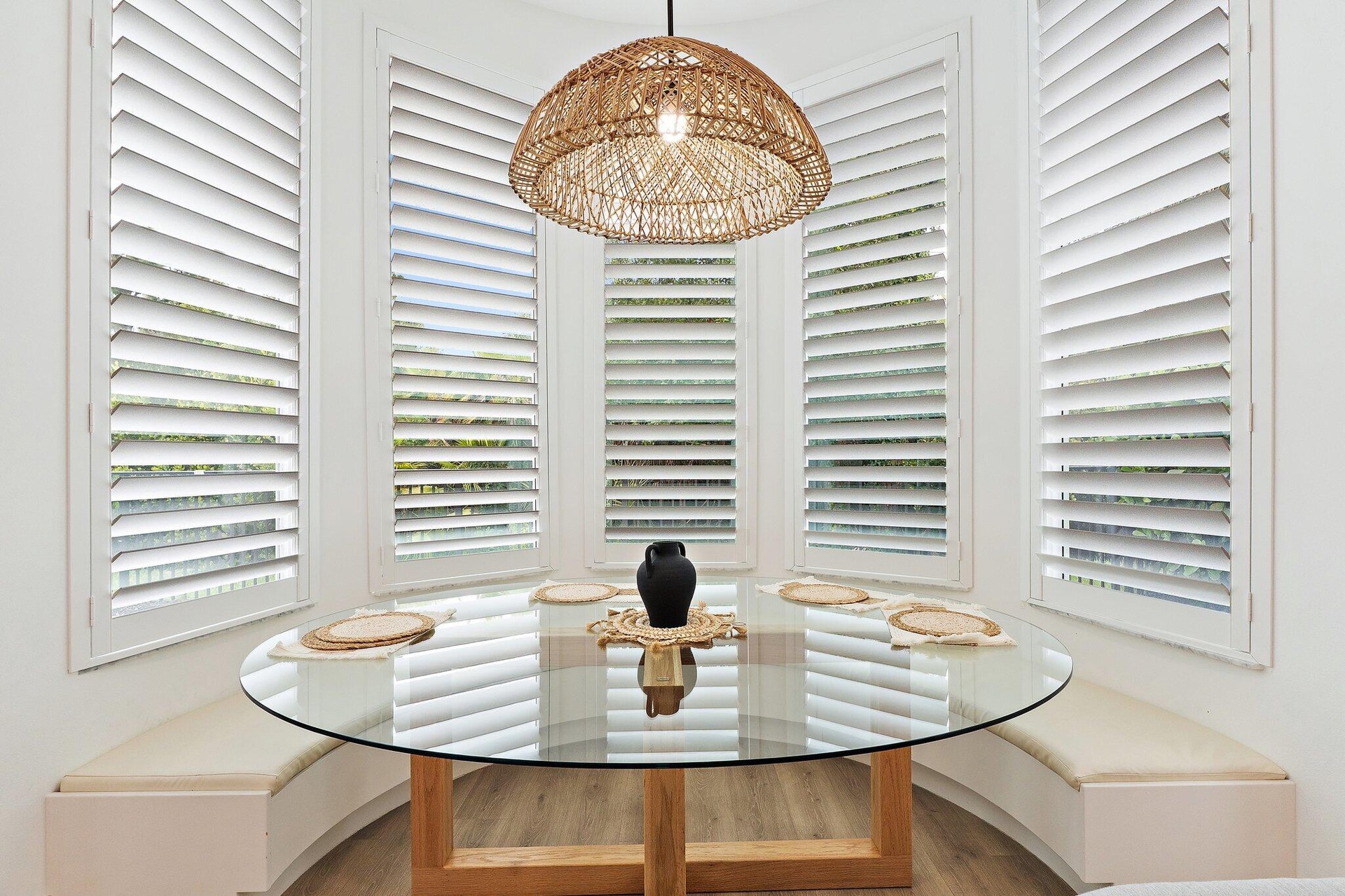 Breakfast nook with round glass table, built-in bench seating, and bay window