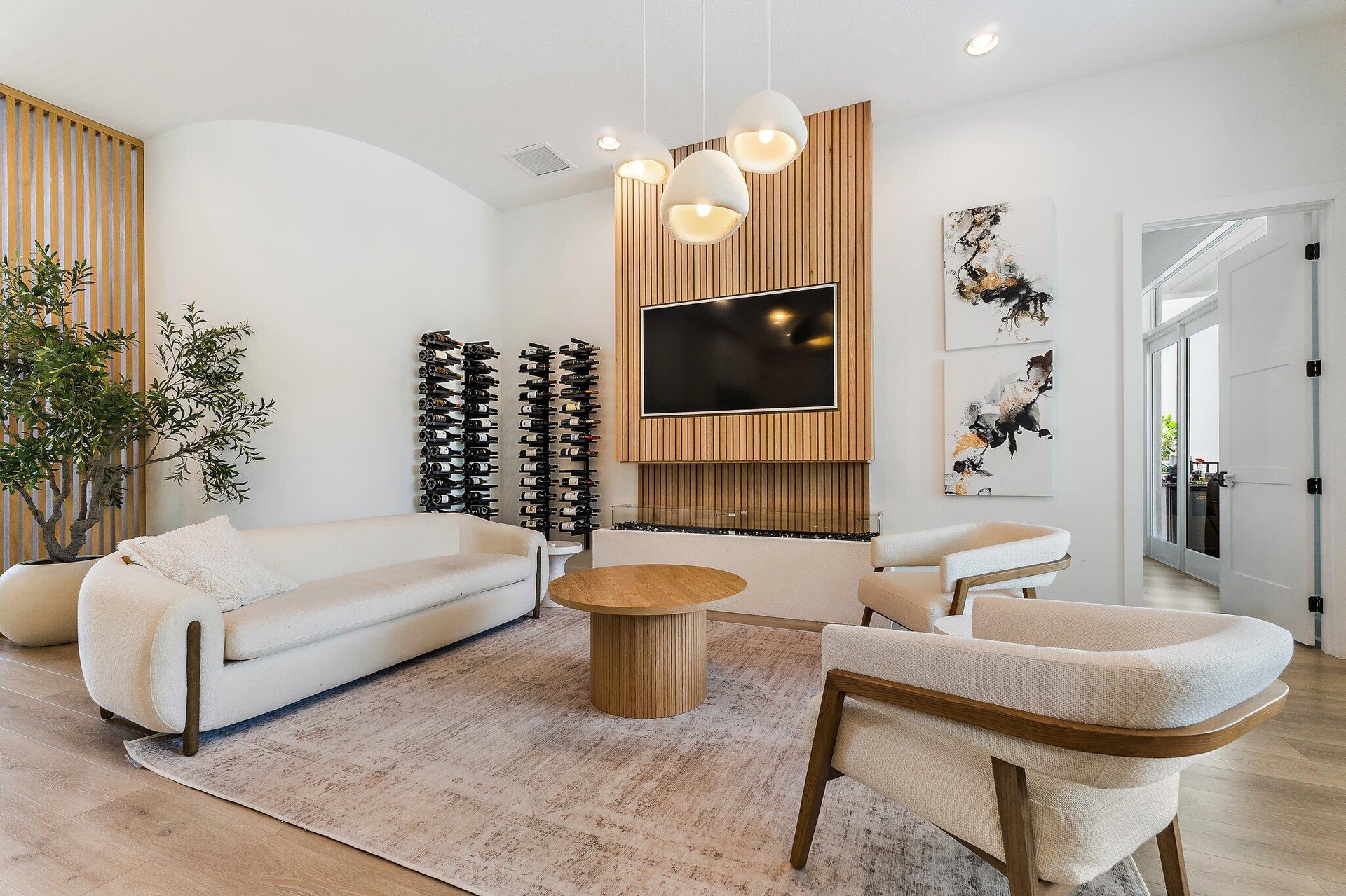 Living room with white sofa, wood accent wall, built-in wine display, and mounted TV