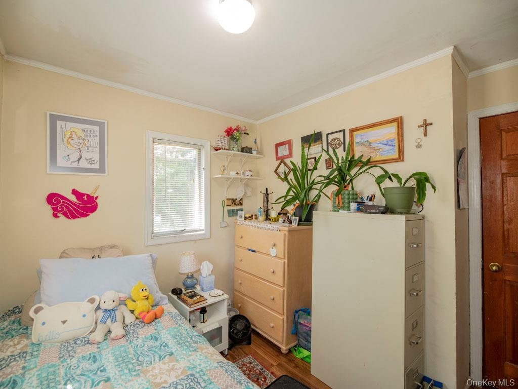 Bedroom with crown molding and wood finished floors