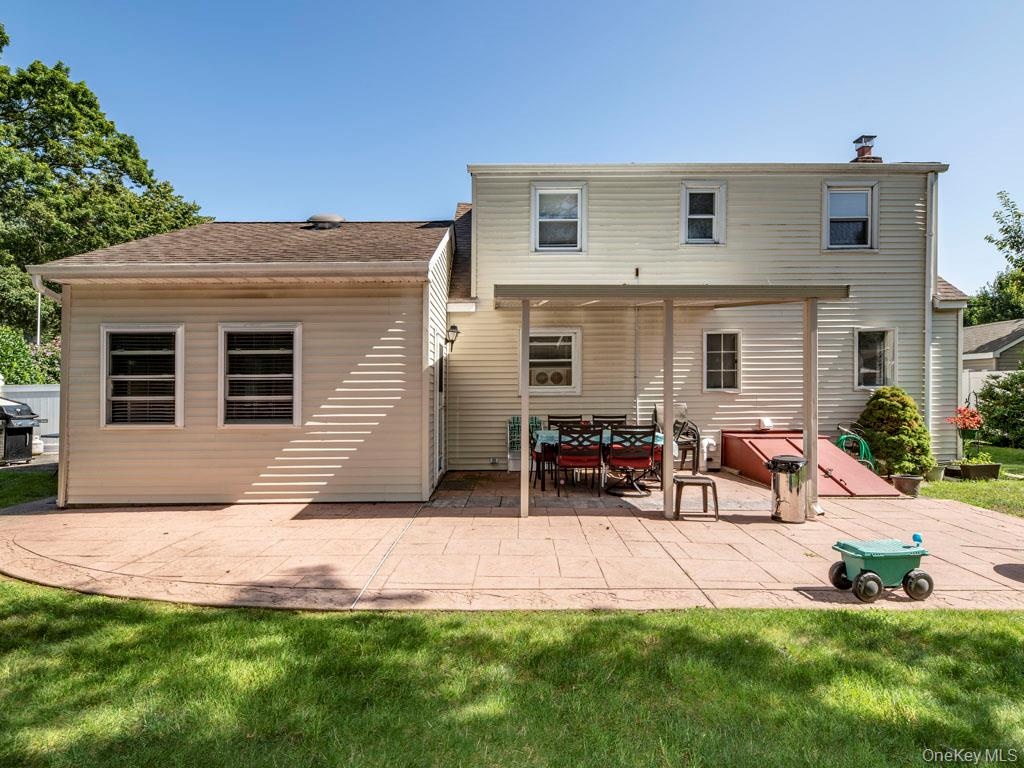 Rear view of property featuring a patio, a yard, and a chimney