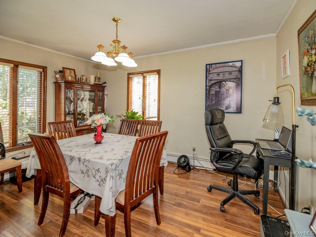 Dining space with crown molding, a chandelier, and wood finished floors