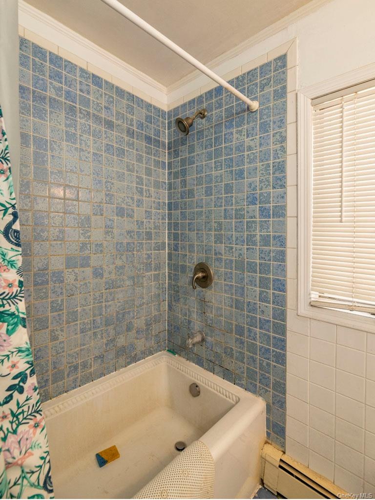 Bathroom featuring crown molding, baseboard heating, and shower / tub combo