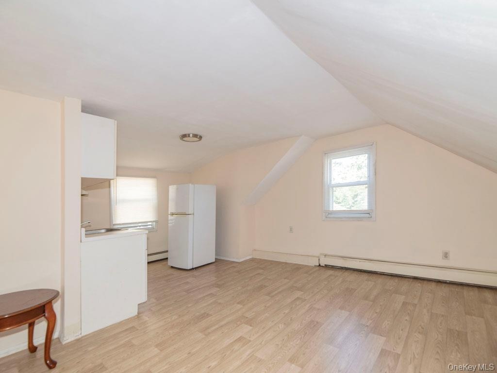 Bonus room featuring light wood finished floors, vaulted ceiling, and a baseboard heating unit