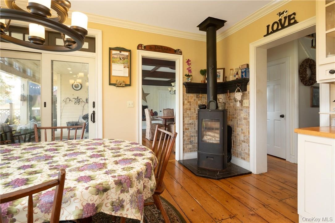 Dining area featuring ornamental molding, hardwood / wood-style floors, ,and a wood stove
