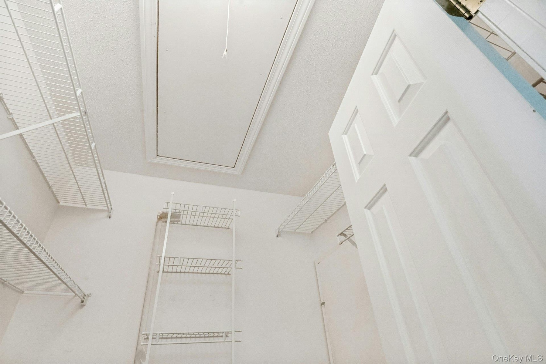 Walk-in closet in the primary bedroom w shelving & access to attic & hot water heater