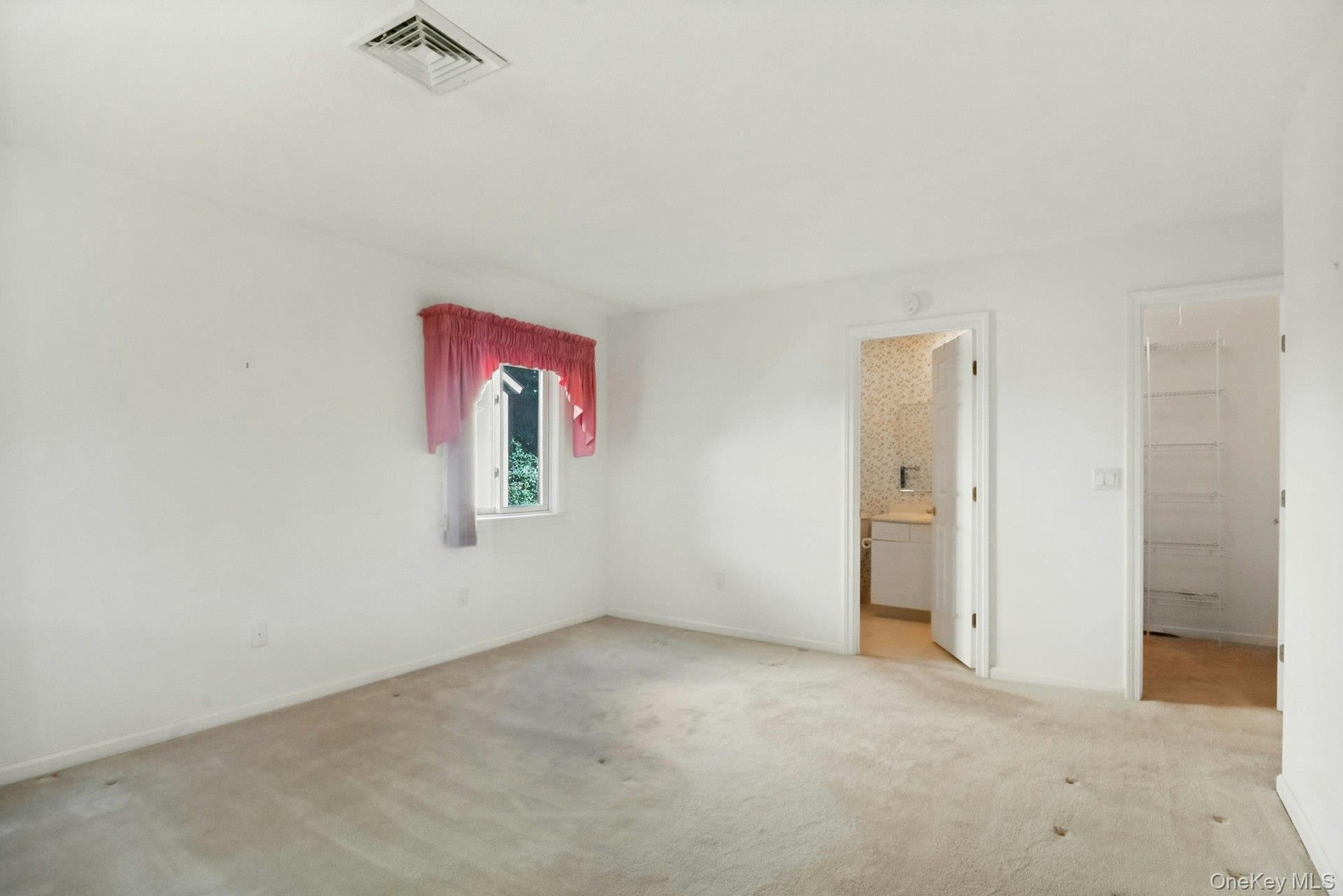 Primary bedroom with a view to the ensuite bath and walk-in closet