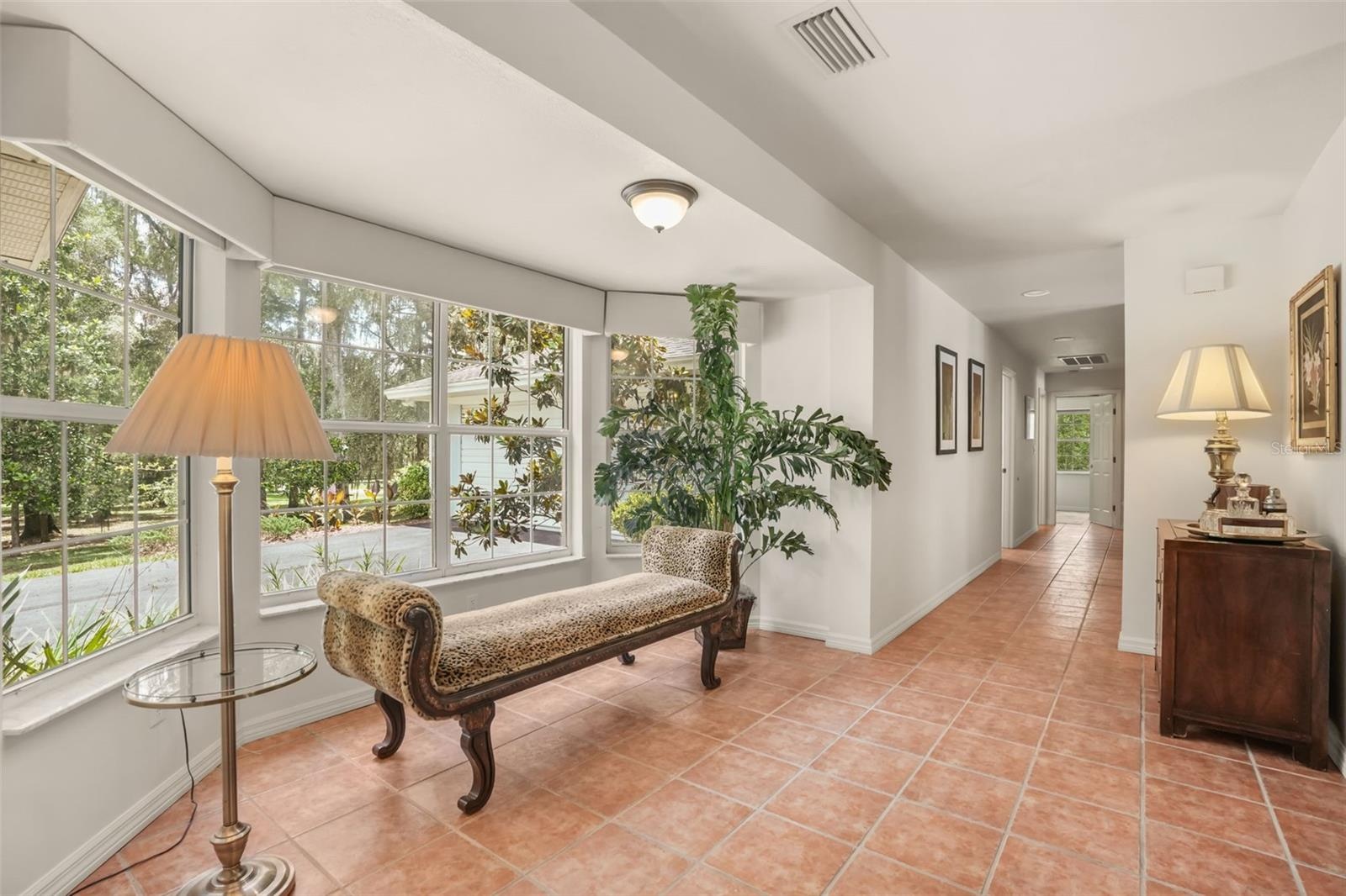 Sun-filled hallway with large windows offering peaceful views of the surrounding landscape.