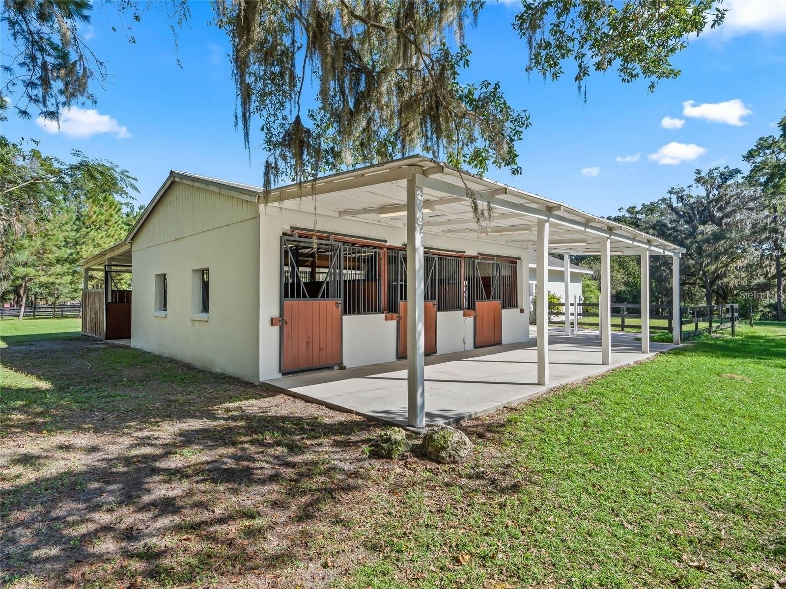 Well-maintained horse barn featuring spacious stalls and a covered work area.