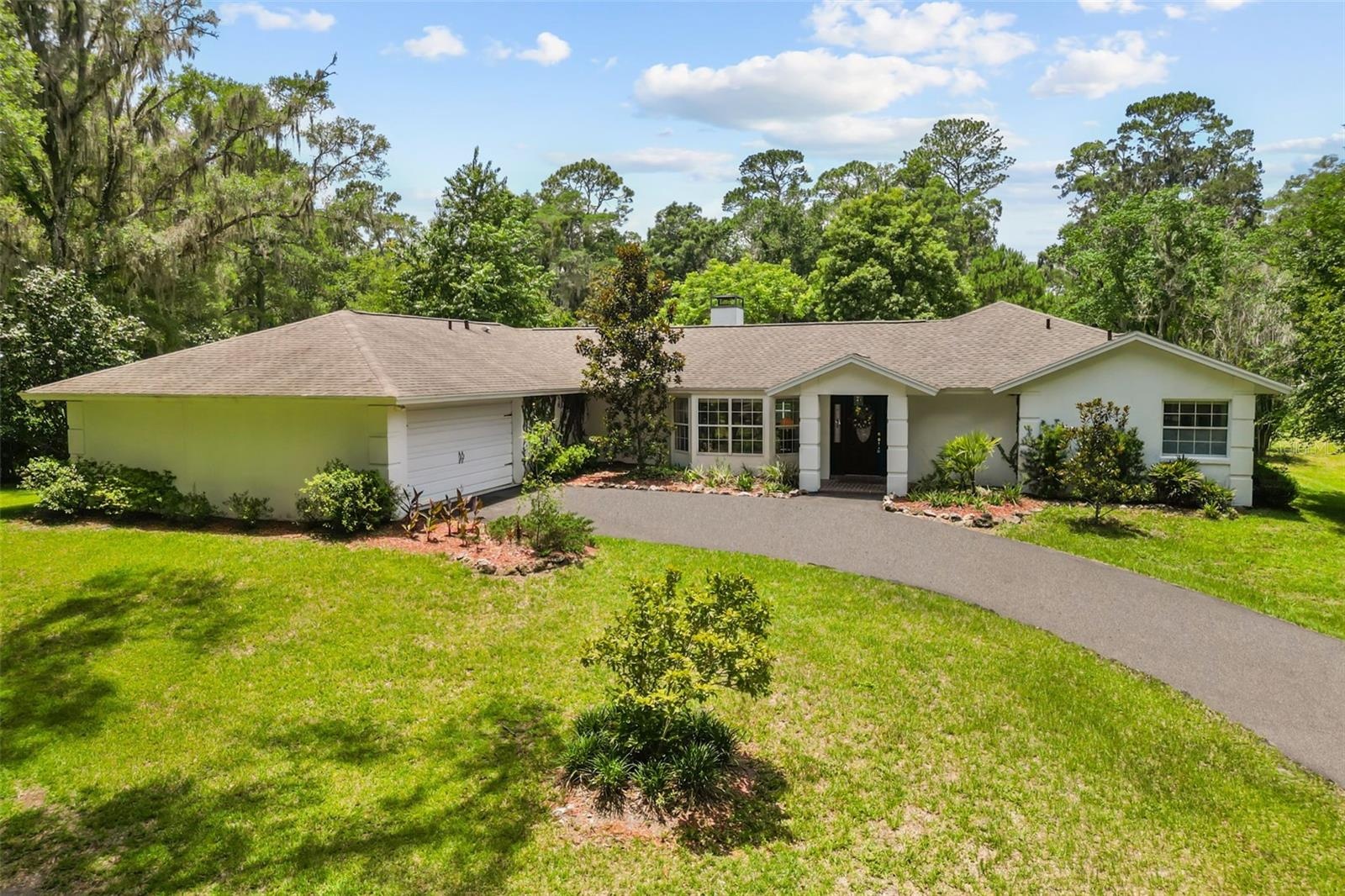 Welcoming front elevation featuring a long paved driveway