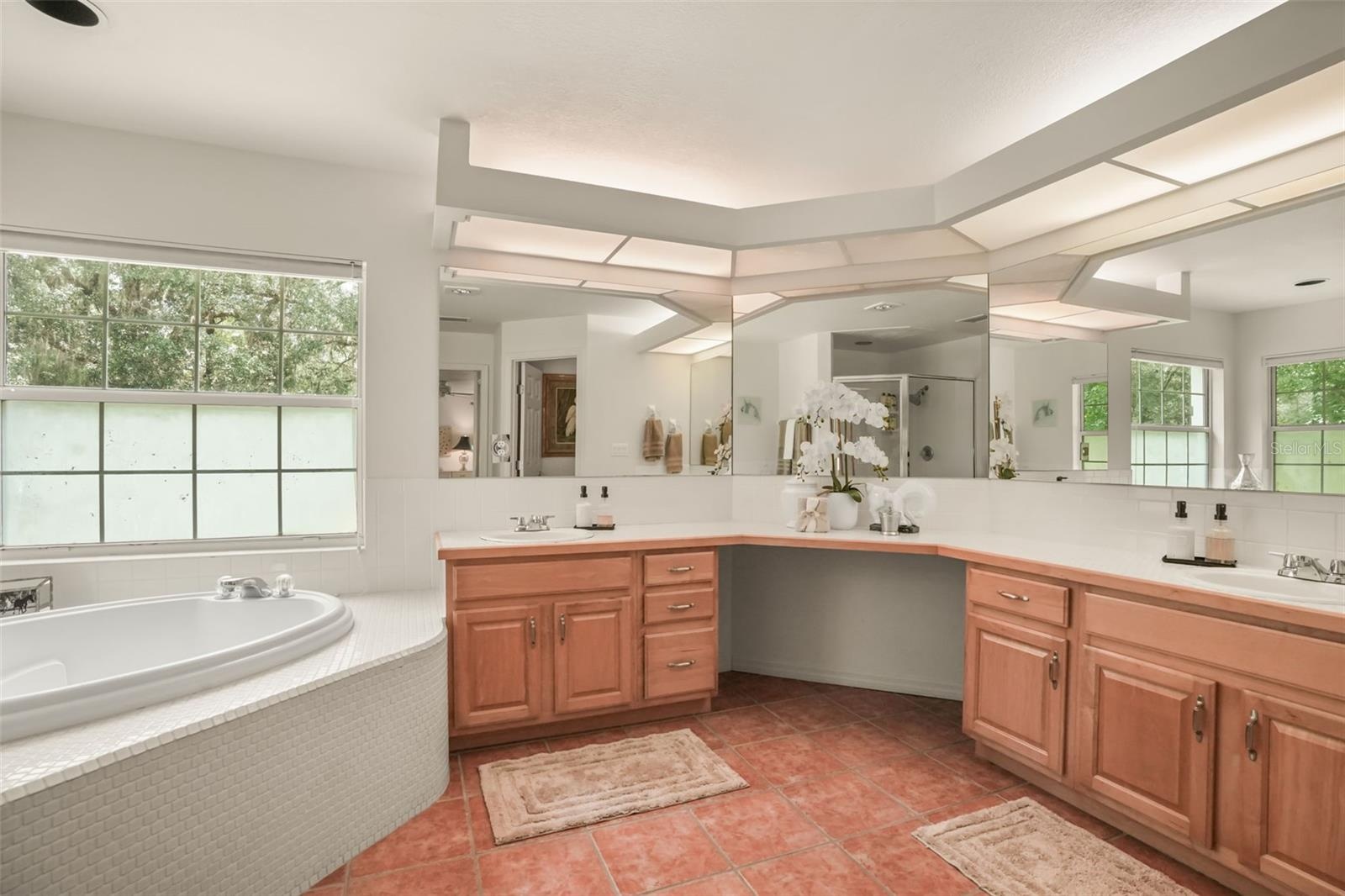 Spacious primary bathroom featuring dual vanities, expansive counter space, and a relaxing soaking tub.