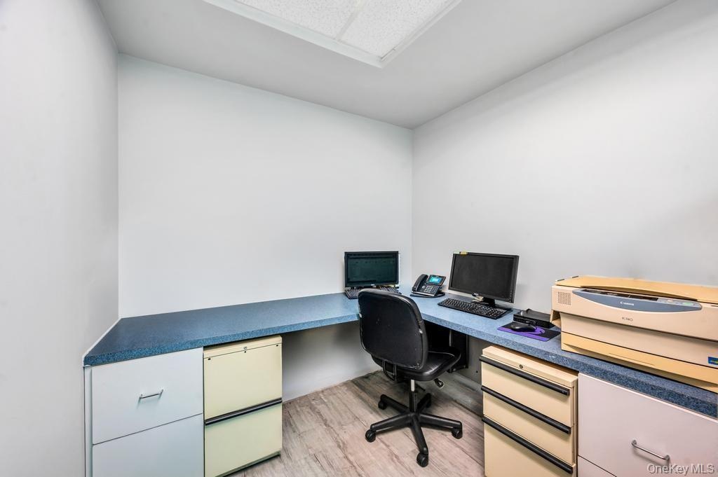 Corner workspace with a light blue speckled countertop, recessed ceiling lighting, and wood-finish flooring