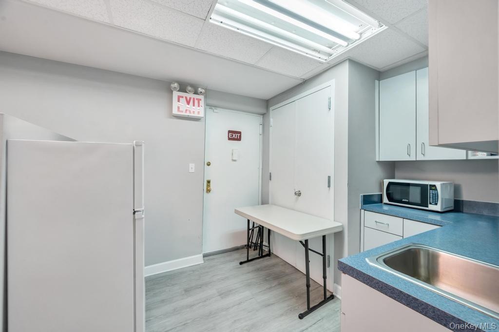 Functional kitchen area featuring a stainless steel sink, light cabinetry, and light wood-finish flooring