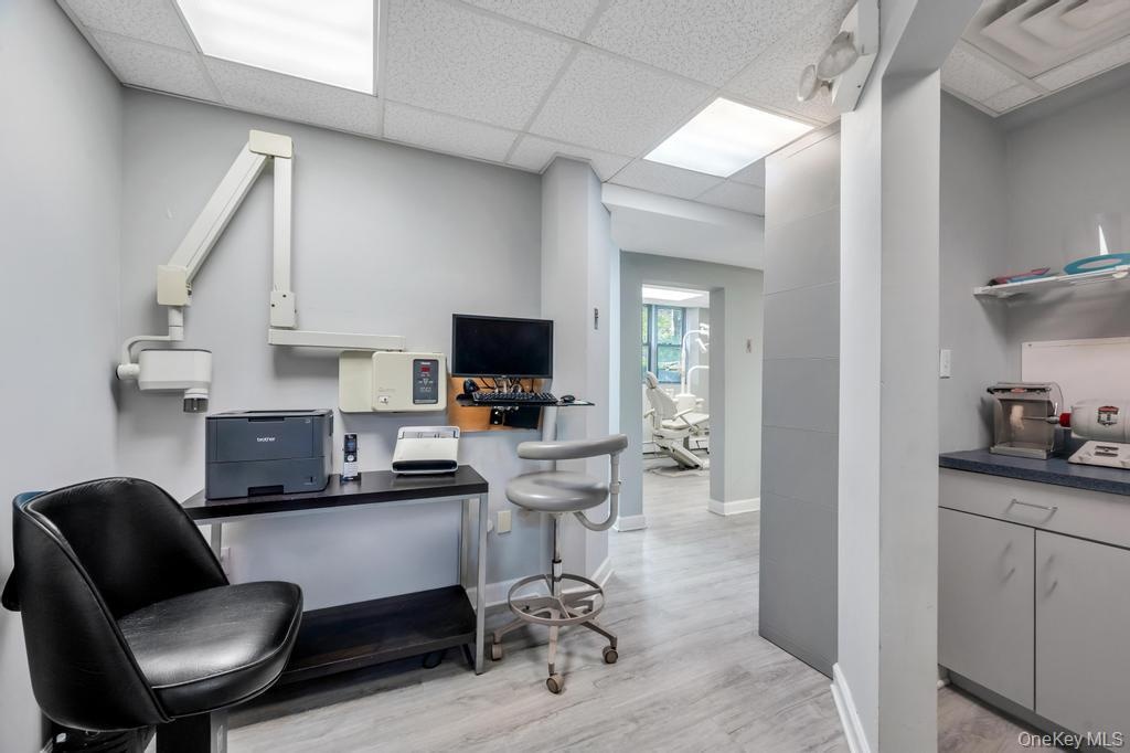Office space featuring wood-finish flooring, drop ceiling with integrated lighting, and light gray wall paint