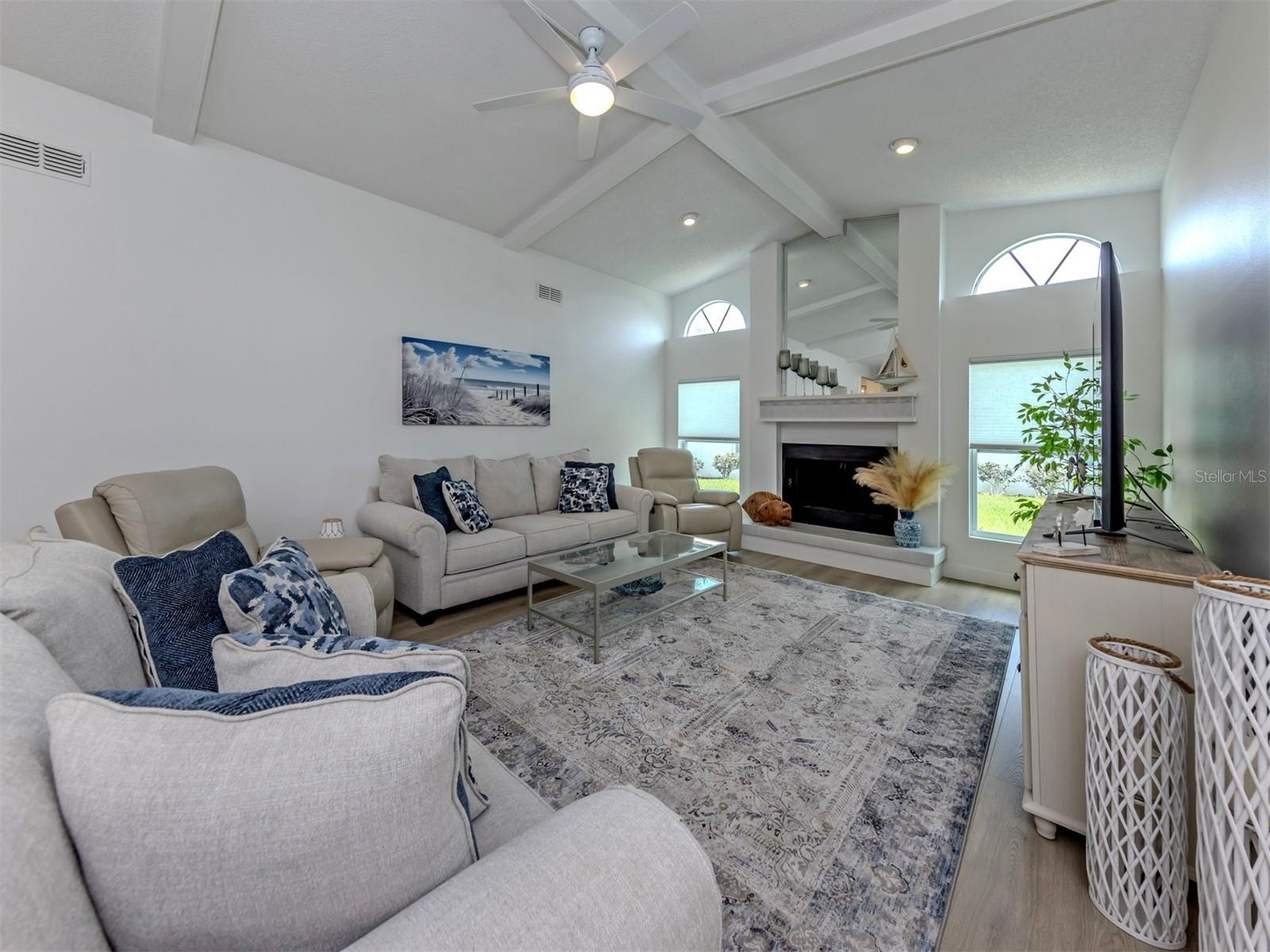 This large family room with soaring ceilings includes a wood burning fireplace