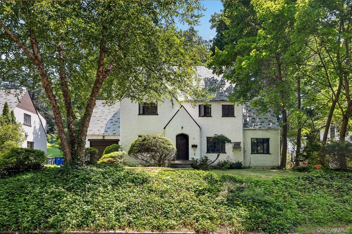 Tudor-style house featuring a high end roof and stucco siding