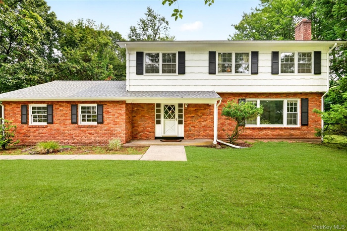 Traditional two-story residence featuring a red brick and white siding exterior