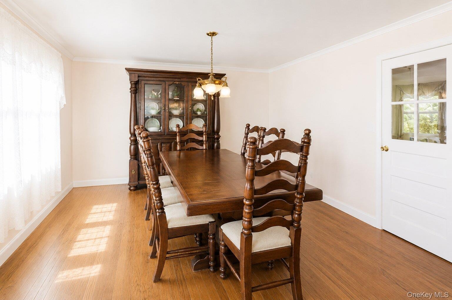 Wood-finish flooring anchors this room, complemented by a multi-pane glass door and a window with sheer coverings