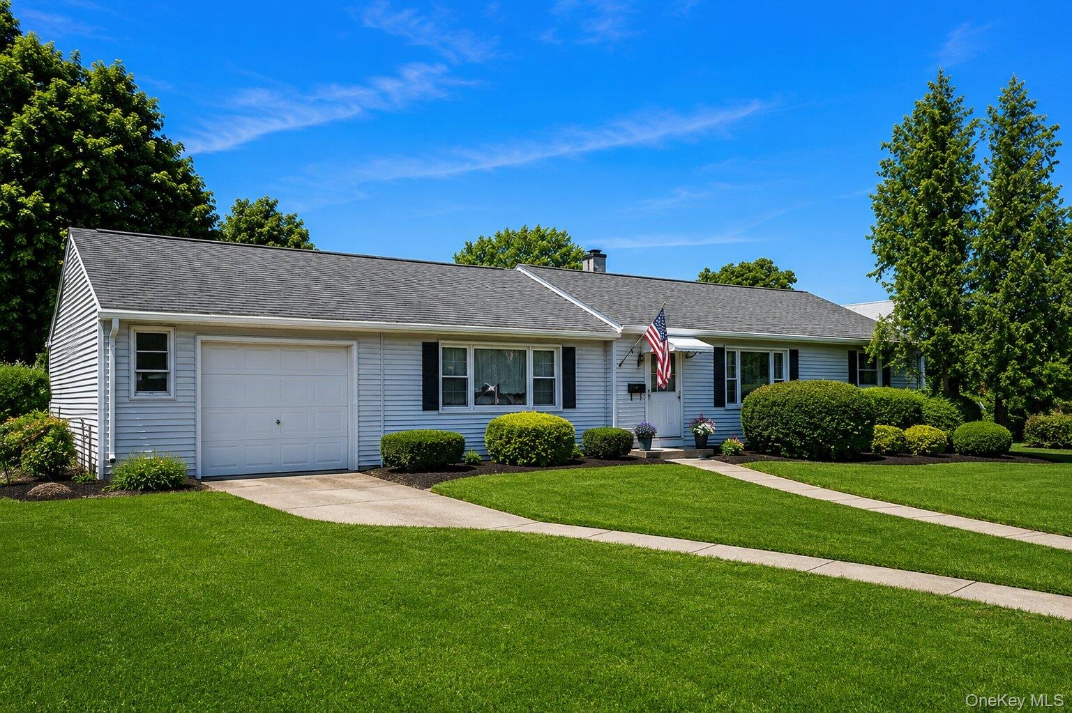 Ranch-style residence featuring light-colored siding and a dark shingle roof