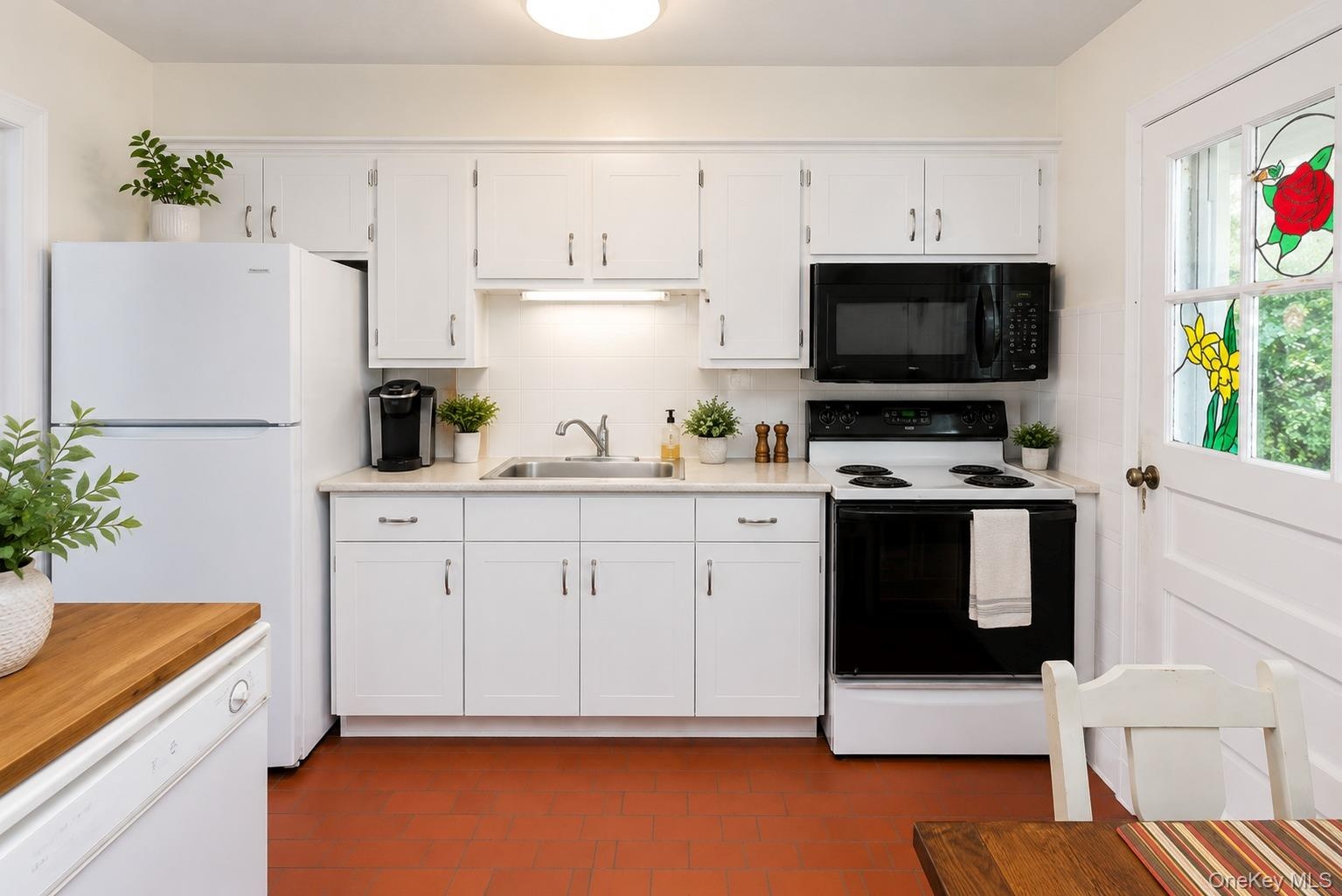 Kitchen featuring white cabinetry, a stainless steel sink, and light-toned countertops