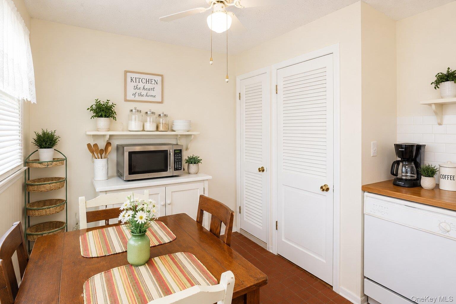Compact kitchen space featuring a wood-finish dining table, white built-in cabinetry, and white louvered closet doors