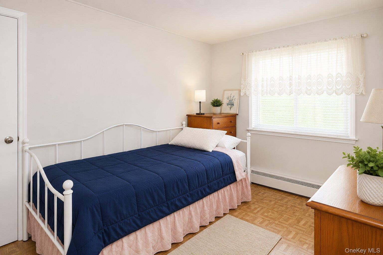VIRTUALLY STAGED. Room featuring neutral wall tones, patterned wood-finish flooring, and a large window with blinds and valance