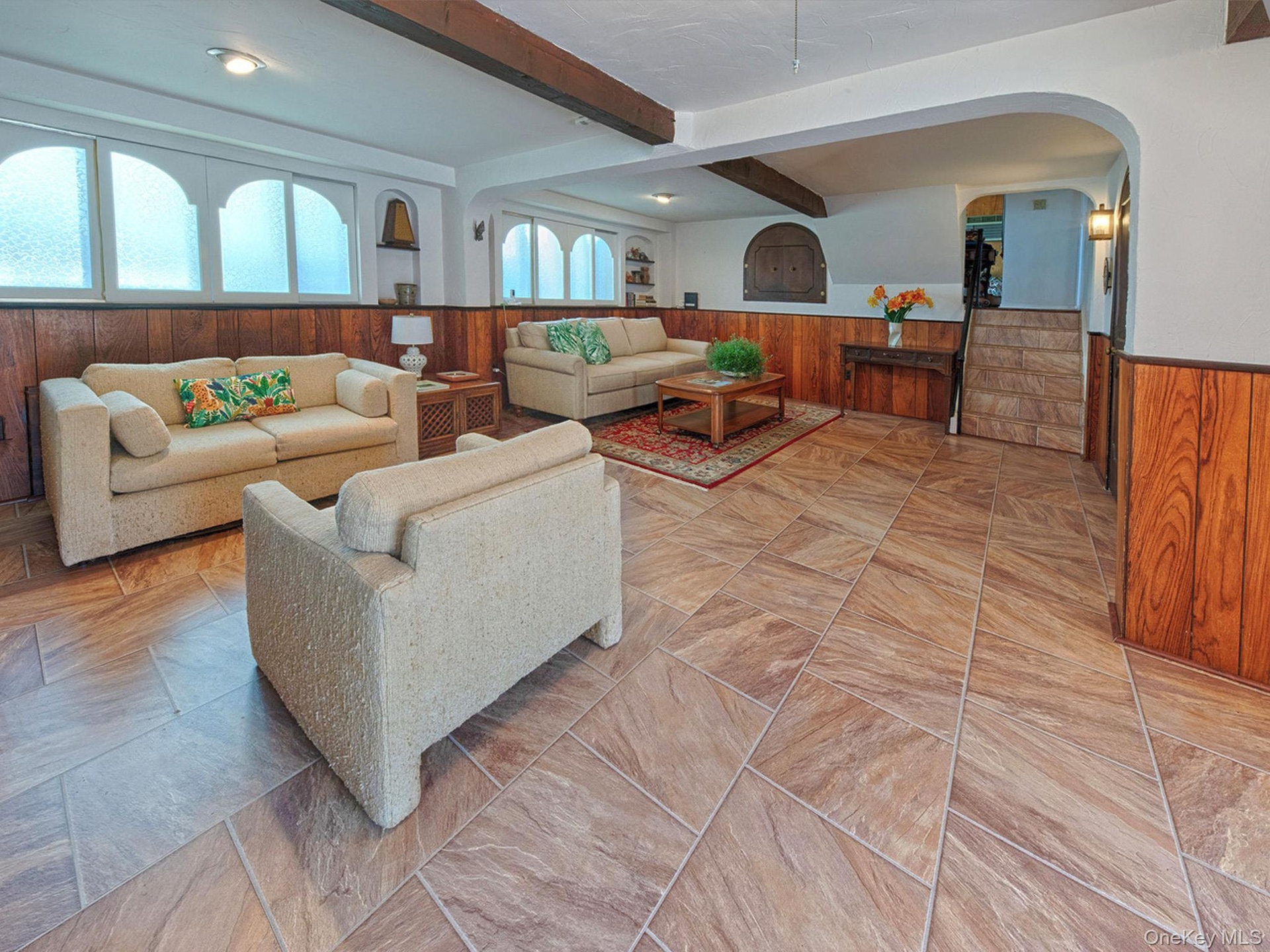 Spacious living area featuring large format tile flooring and wood paneling