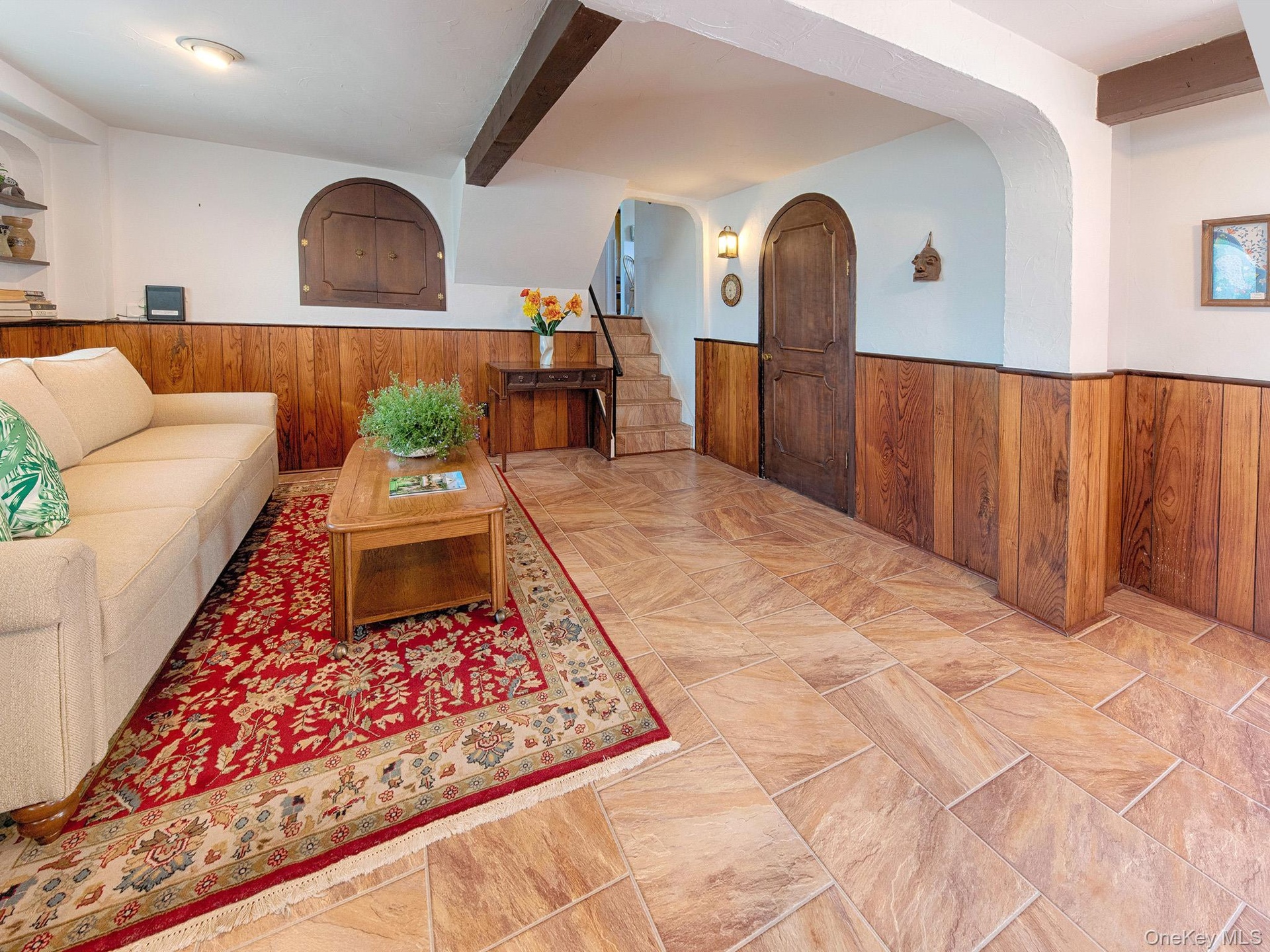Spacious living area featuring large format tile flooring and wood paneling