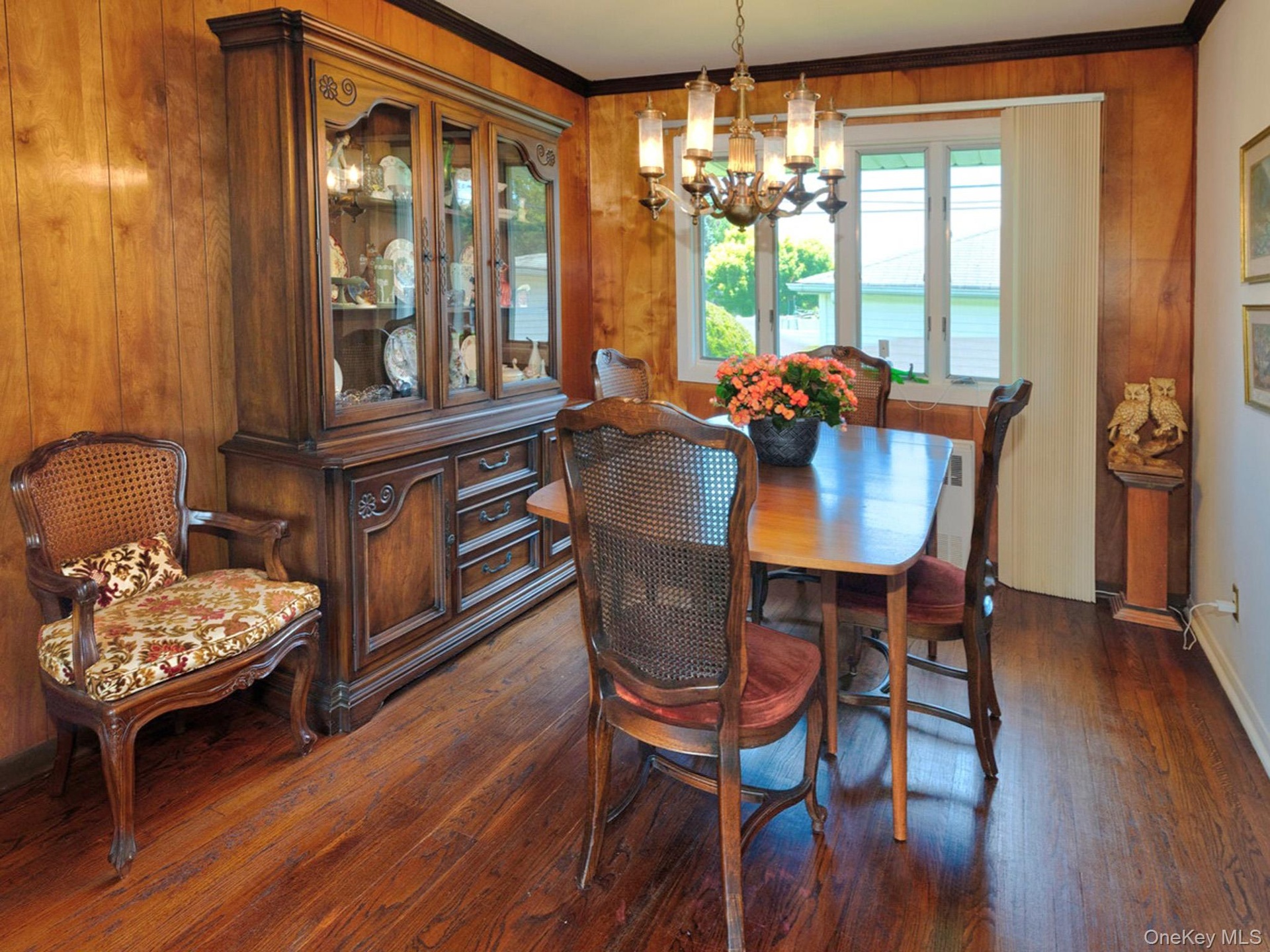 Dining space featuring wood-finish flooring, wood paneling, and a multi-pane window
