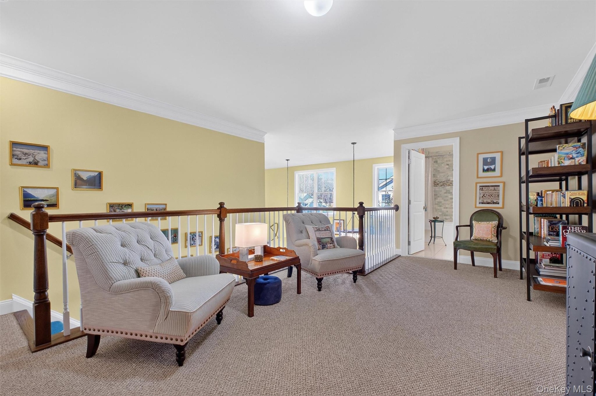 Living area with ornamental molding, light colored carpet, and an upstairs landing