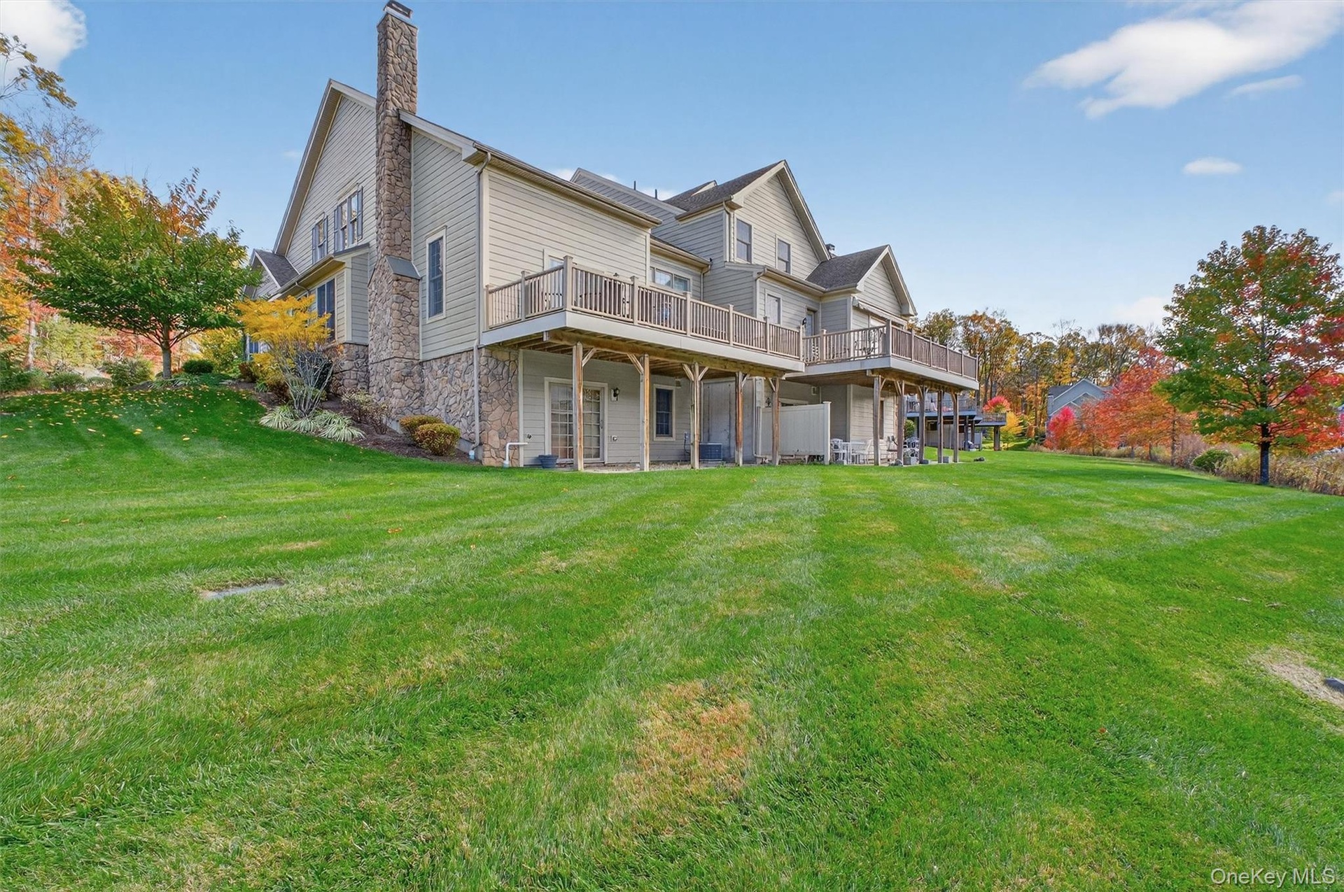 Back of house featuring a yard, a deck, a chimney, and a patio area
