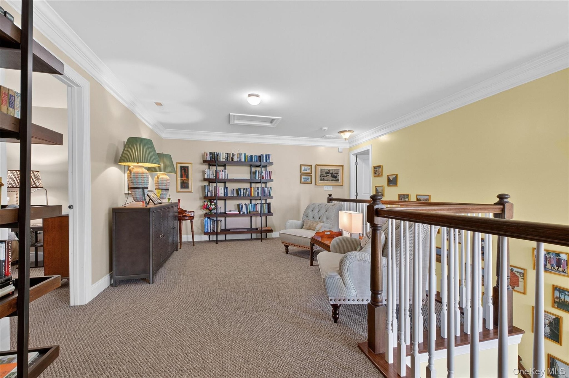 Living area featuring attic access, crown molding, and carpet