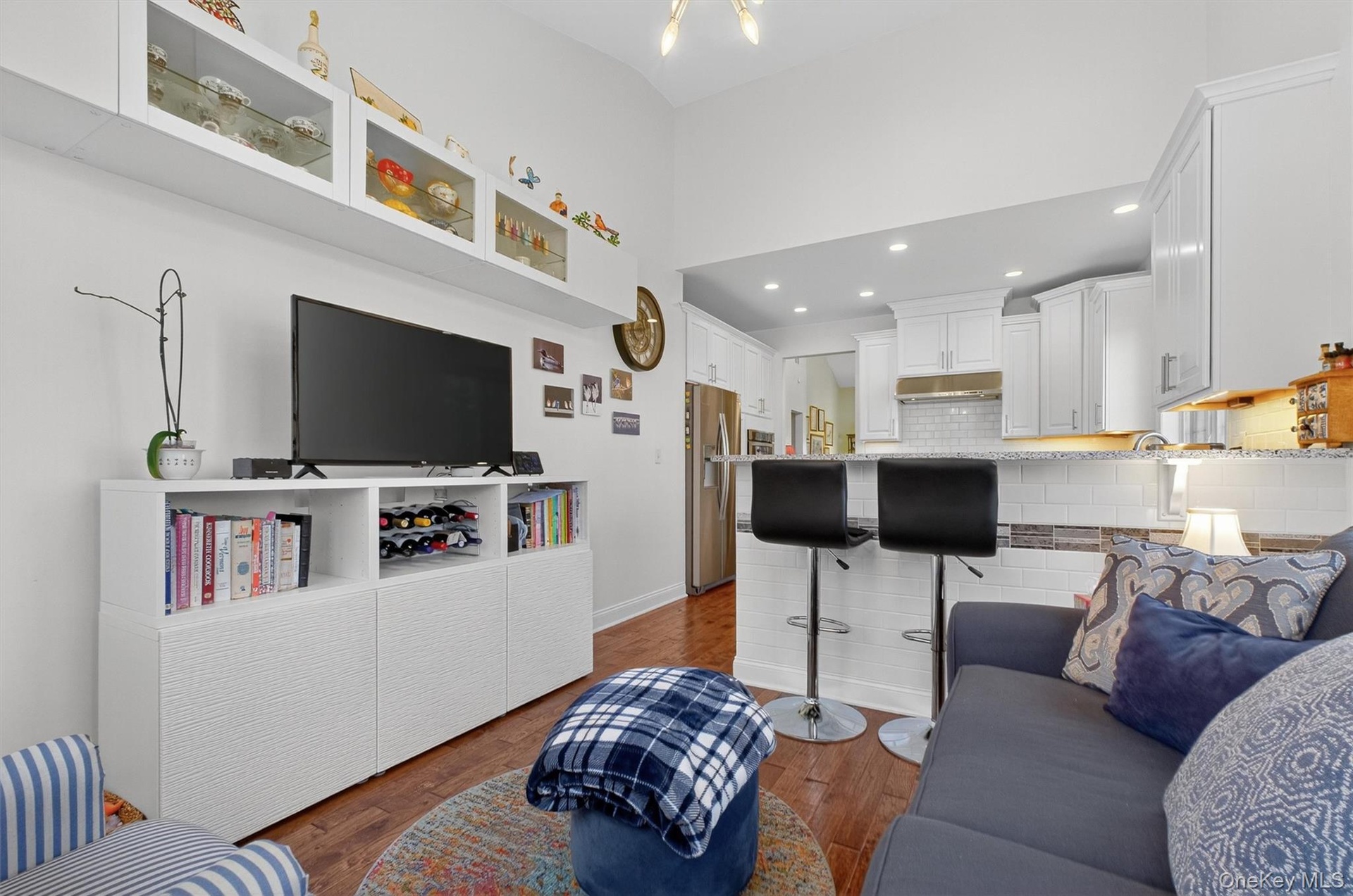 Living area with dark wood-style flooring, recessed lighting, and a high ceiling
