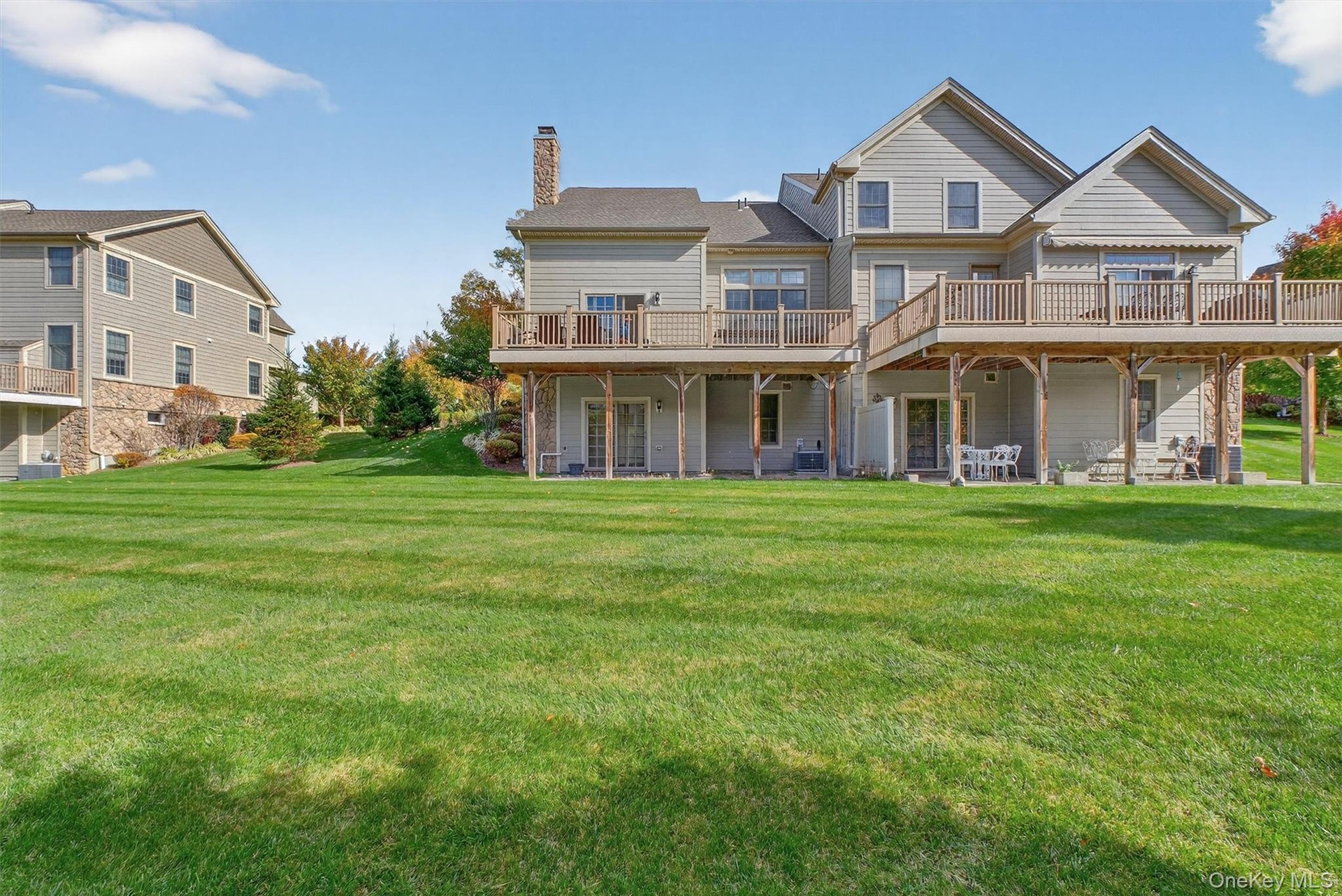 Rear view of house with a yard, a wooden deck, a chimney, and a patio area