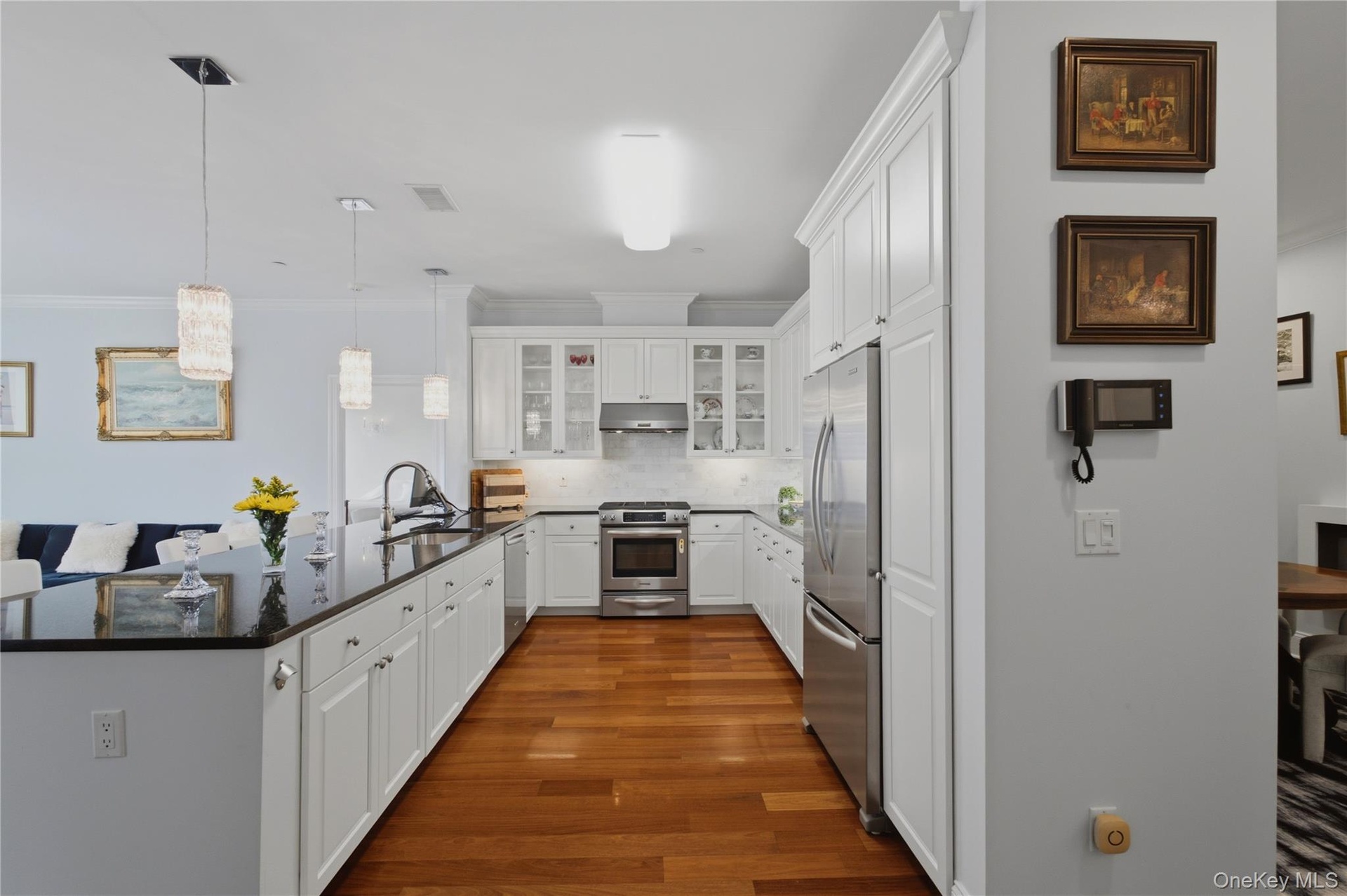 Stainless steel appliances, elegant pendant lighting, and an expansive counter create a stylish and functional kitchen.