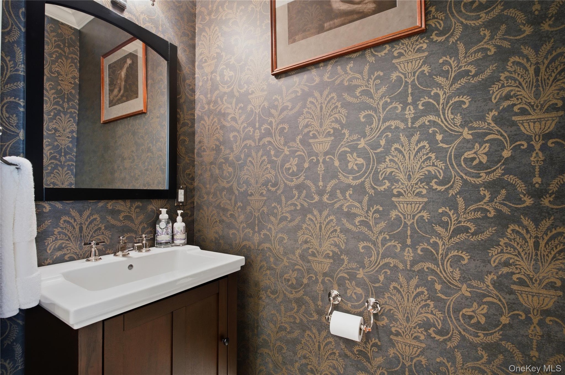 Stylish powder room featuring designer wall-paper and tasteful finishes.
