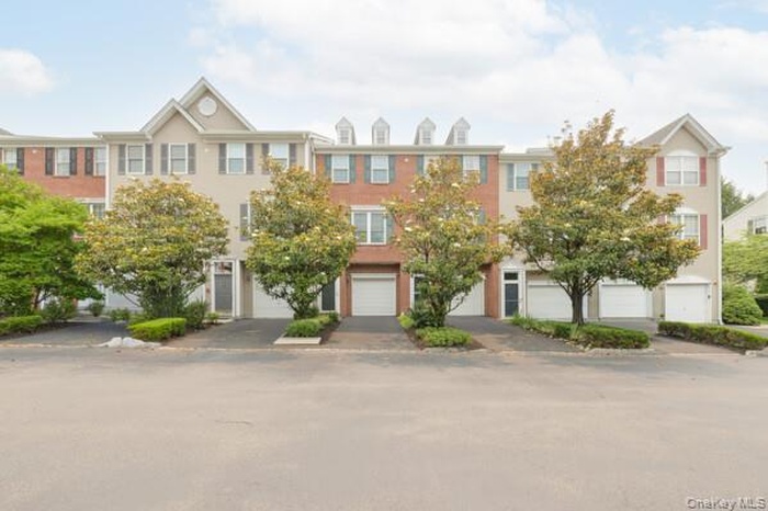 Townhome exterior featuring a dormer roofline, red brick accents.