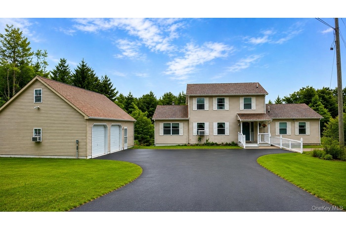 Expansive asphalt driveway leading to a two-story residence and a detached two-car garage