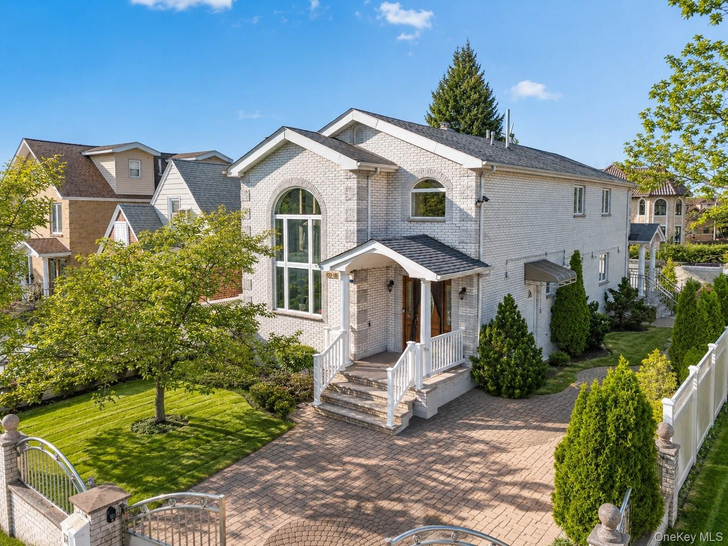 Elegant brick Colonial with a two-story arched entry portico, white railing details, and a circular brick driveway
