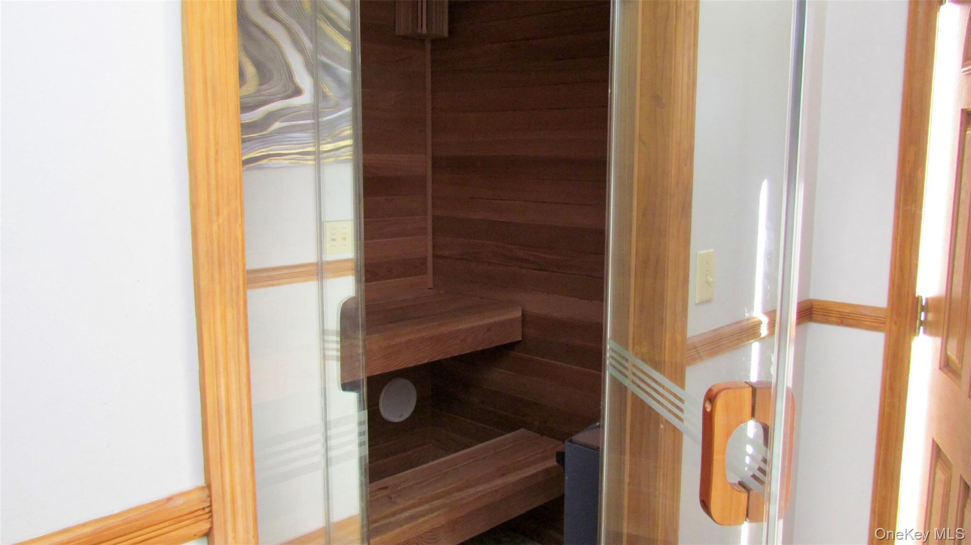 Integrated sauna with clear glass door, wooden handle, and tiered wooden benches